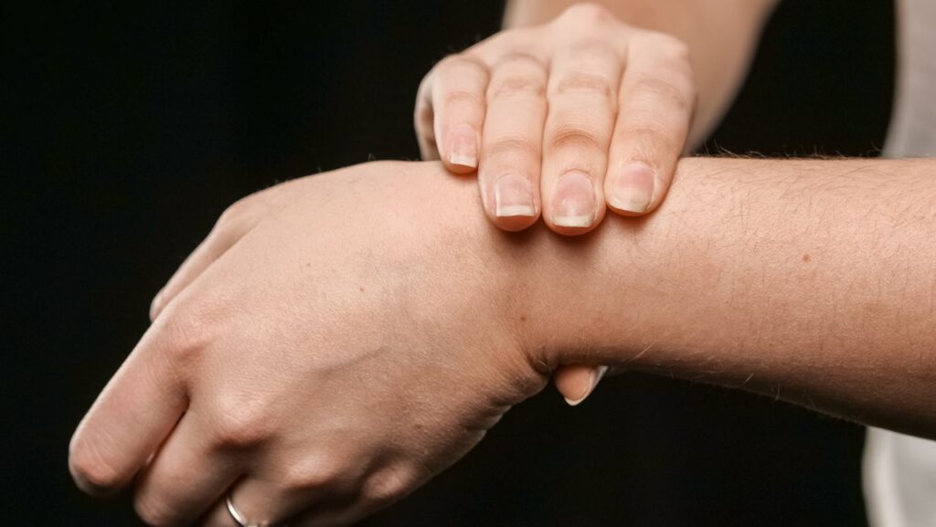 Person gently holding their own wrist with the other hand